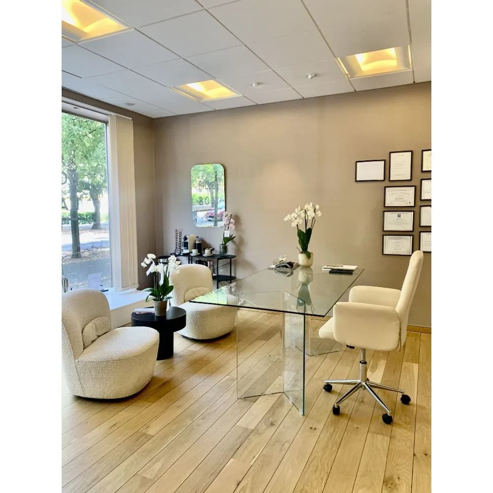 Konsultationsrum med glasskrivbord och diplomvägg hos Cosmetic Medical Clinic i Malmö