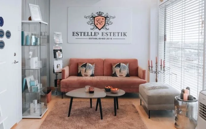 Väntrum med rosa soffa och logotyp hos Estelles Estetik i Limhamn