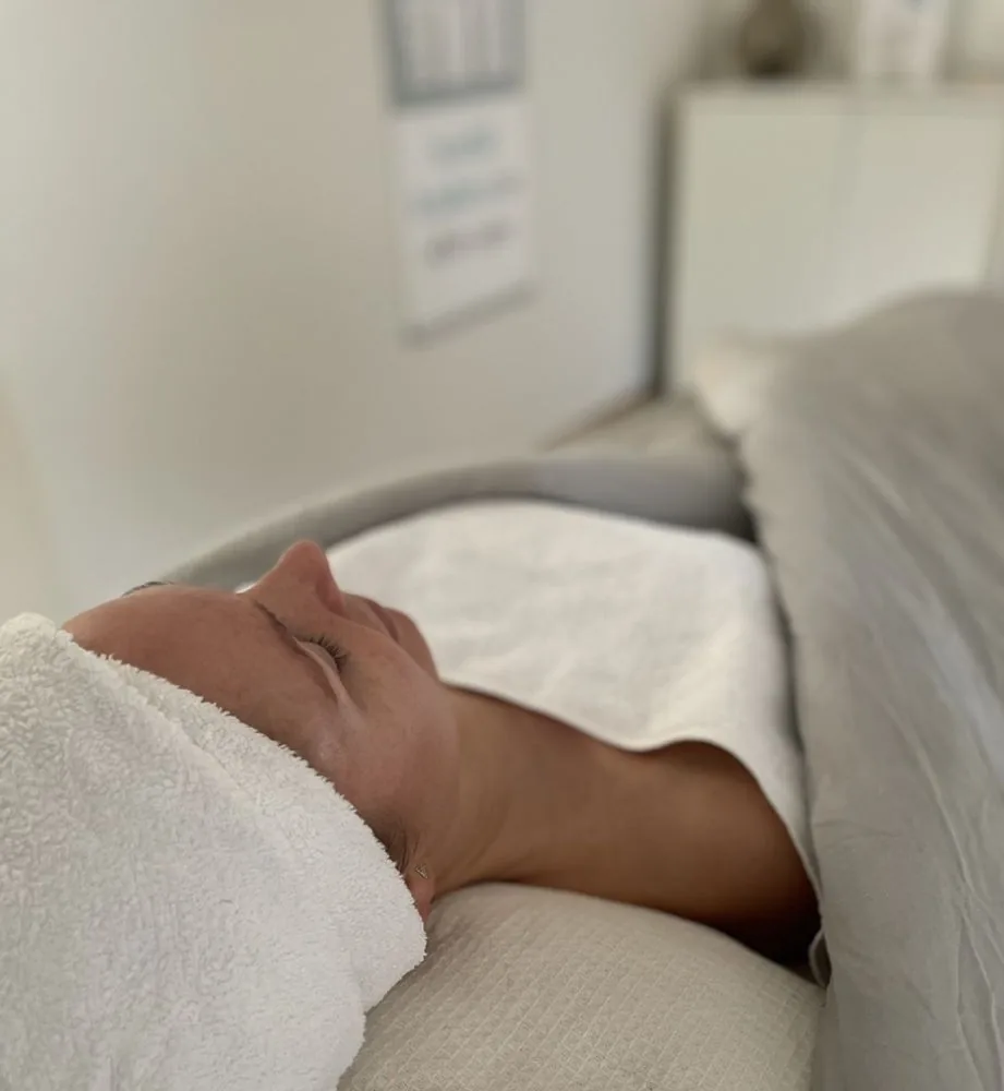 Kund med handduk om håret vilar under ansiktsbehandling hos Hudterapeuterna i Hyllie